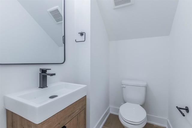 bathroom with vaulted ceiling, vanity, and toilet