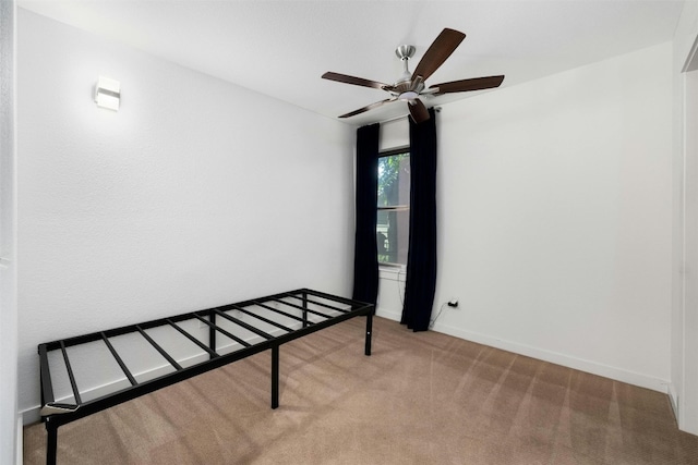 carpeted empty room featuring ceiling fan and baseboards