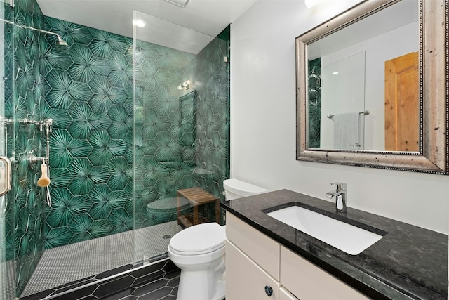 bathroom featuring toilet, tile patterned flooring, a tile shower, and vanity