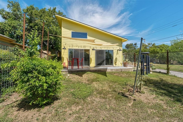 back of property with fence, a lawn, and a patio