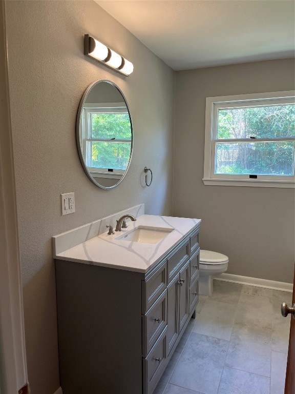 bathroom with a wealth of natural light, toilet, vanity, and tile patterned floors