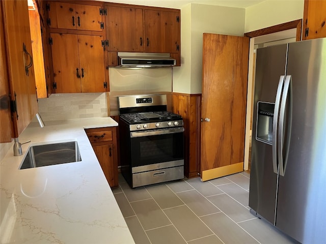 kitchen with appliances with stainless steel finishes, range hood, sink, and tile patterned floors