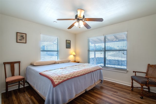 bedroom with ceiling fan, dark wood-type flooring, and multiple windows