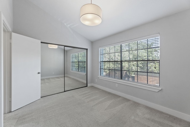 unfurnished bedroom featuring a closet, vaulted ceiling, and light carpet