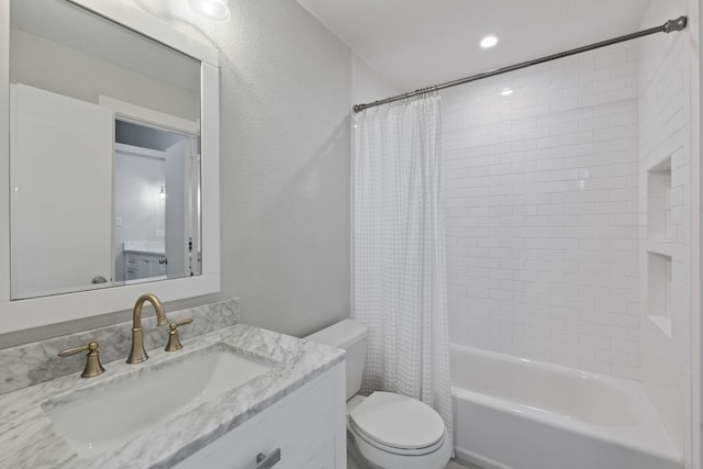 bathroom featuring a textured wall, vanity, shower / bath combination with curtain, and toilet