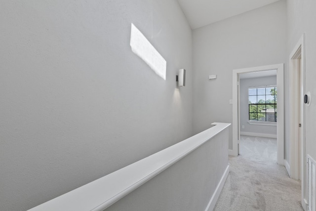 hall featuring vaulted ceiling and light carpet