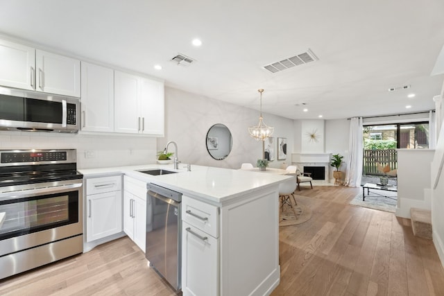 kitchen featuring open floor plan, stainless steel appliances, light countertops, and white cabinets