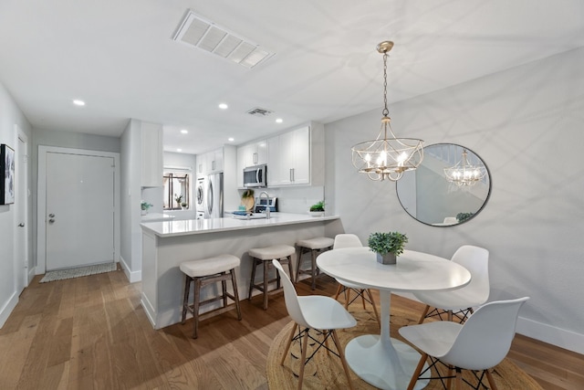 dining area with light wood finished floors, baseboards, visible vents, and recessed lighting