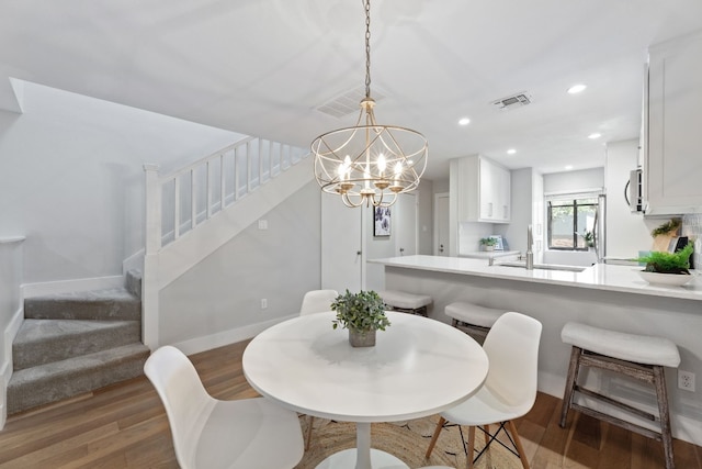 dining space featuring dark wood-type flooring, sink, and a chandelier