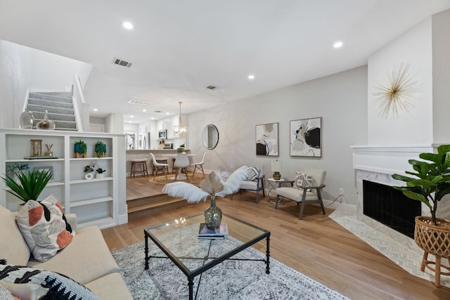 living room featuring light wood finished floors, baseboards, visible vents, a fireplace, and recessed lighting