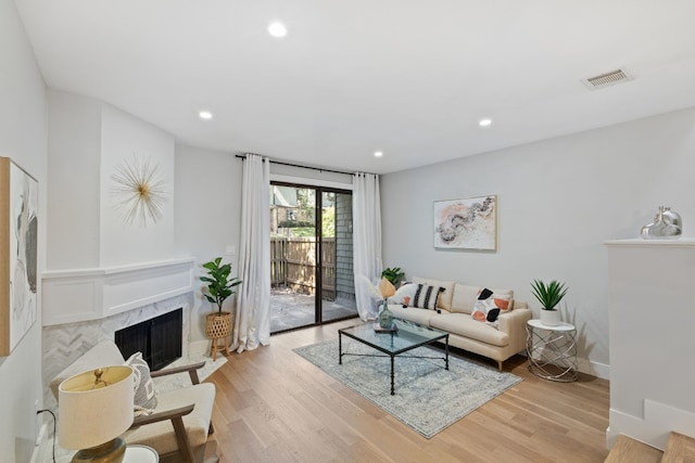 living room with light wood-style floors, a fireplace, visible vents, and recessed lighting