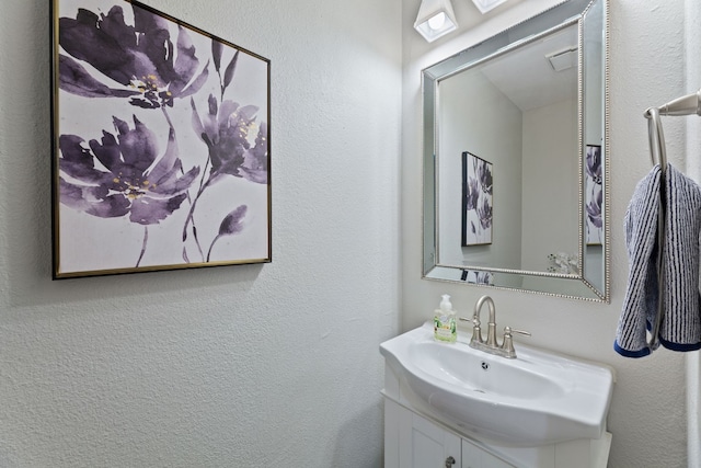 bathroom featuring a textured wall, visible vents, and vanity