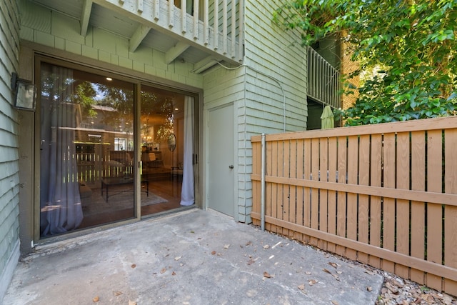 view of exterior entry with a patio area and fence