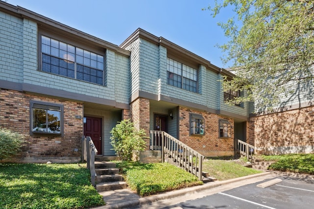 townhome / multi-family property with uncovered parking and brick siding