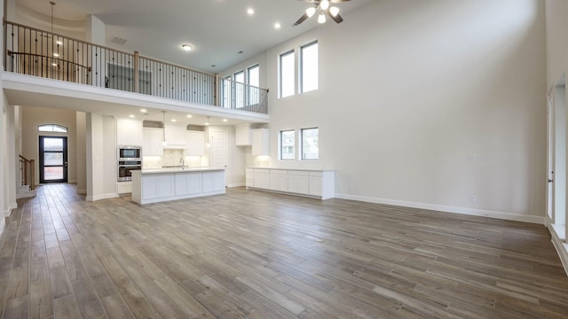 unfurnished living room with a towering ceiling, wood-type flooring, and a healthy amount of sunlight