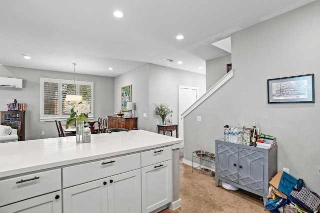 kitchen featuring light carpet, hanging light fixtures, white cabinetry, and a wall mounted air conditioner