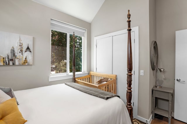 bedroom featuring a closet, high vaulted ceiling, hardwood / wood-style floors, and a nursery area