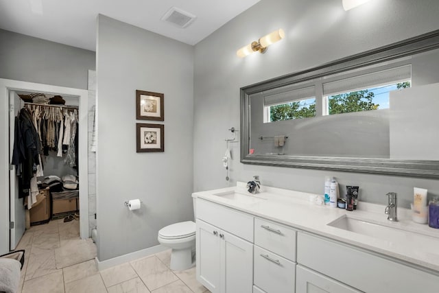 bathroom with toilet, double vanity, and tile patterned flooring