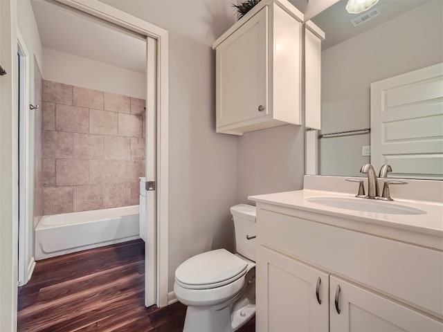 full bathroom featuring hardwood / wood-style floors, vanity, toilet, and tiled shower / bath combo