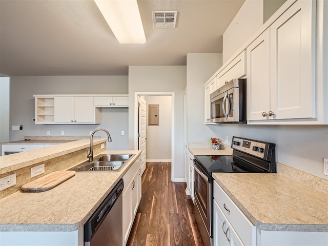 kitchen with dark wood-type flooring, white cabinets, a center island with sink, sink, and appliances with stainless steel finishes