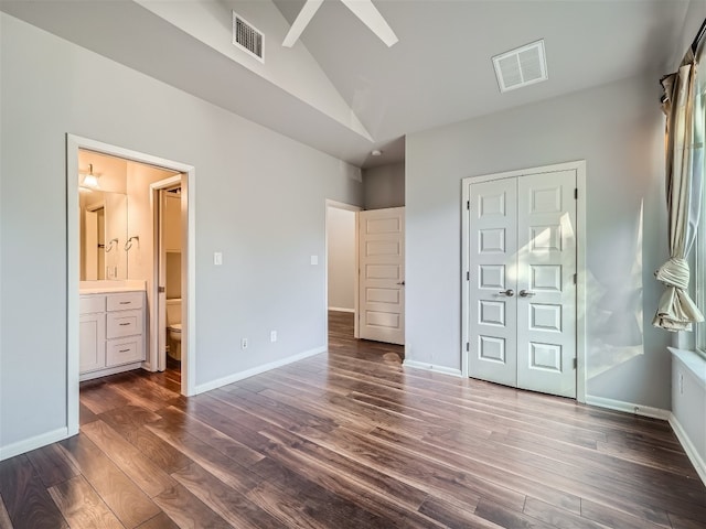 unfurnished bedroom featuring vaulted ceiling, dark hardwood / wood-style floors, ceiling fan, connected bathroom, and a closet