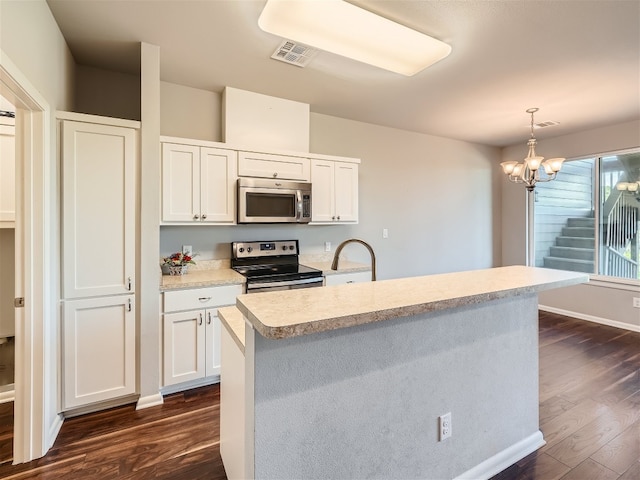 kitchen featuring dark hardwood / wood-style flooring, stainless steel appliances, white cabinetry, and hanging light fixtures