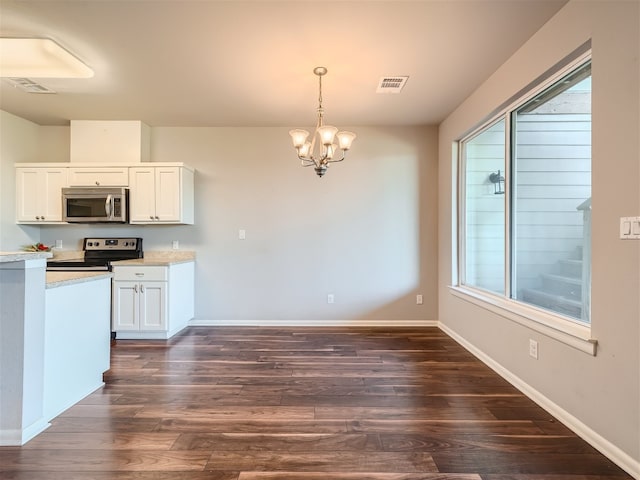 kitchen with appliances with stainless steel finishes, dark wood-type flooring, an inviting chandelier, white cabinetry, and hanging light fixtures