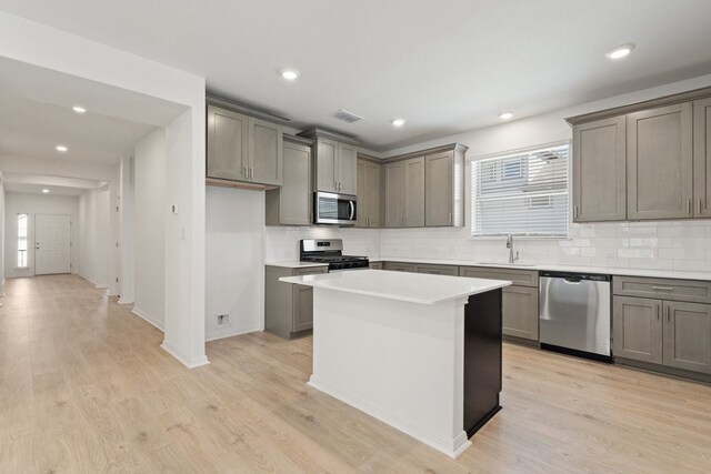 kitchen featuring light hardwood / wood-style flooring, a healthy amount of sunlight, stainless steel appliances, and a kitchen island