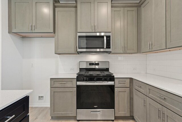 kitchen featuring gray cabinets, light hardwood / wood-style flooring, stainless steel appliances, and tasteful backsplash