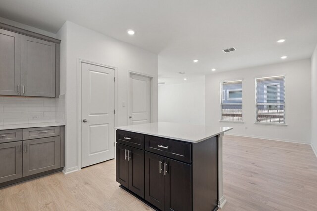 kitchen with a kitchen island, decorative backsplash, and light wood-type flooring