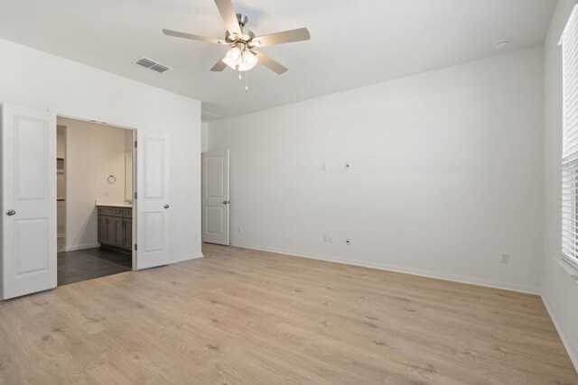 unfurnished bedroom featuring connected bathroom, light hardwood / wood-style floors, and ceiling fan