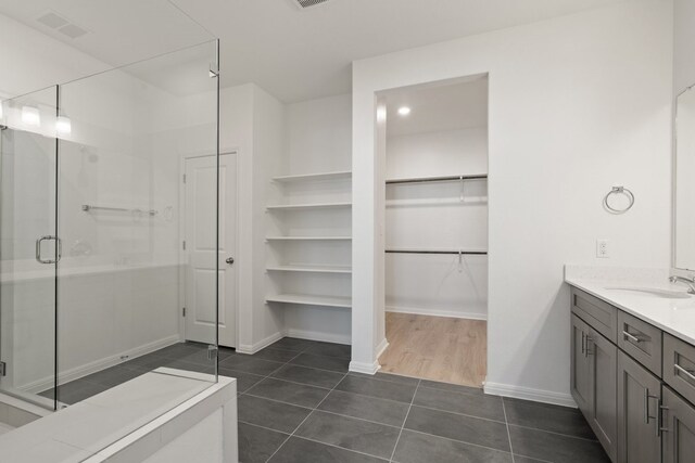 bathroom with a shower with door, vanity, and tile patterned floors