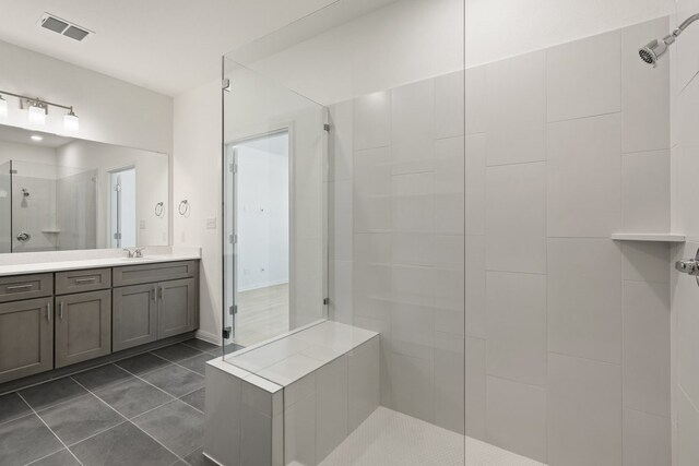 bathroom with vanity, tiled shower, and tile patterned flooring