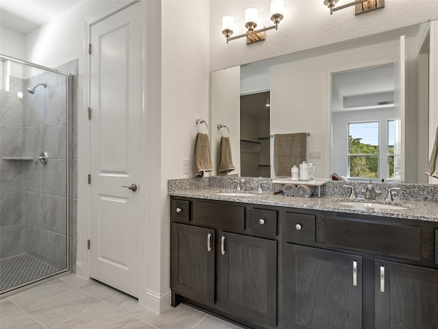 bathroom featuring a textured ceiling, double vanity, walk in shower, and tile patterned floors