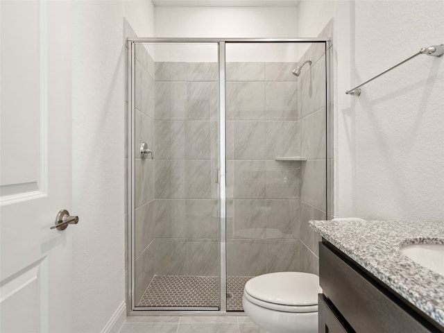 bathroom featuring a shower with door, toilet, vanity, and tile patterned floors