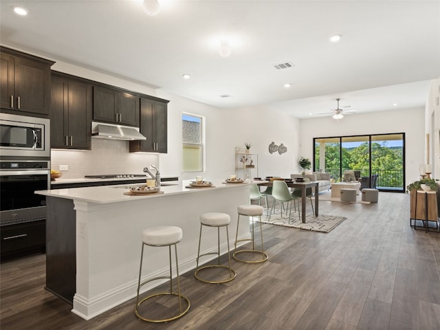 kitchen with appliances with stainless steel finishes, dark wood-type flooring, and decorative backsplash