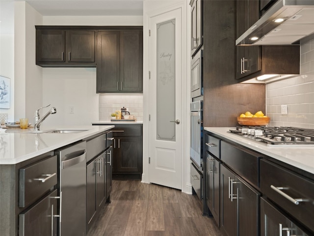 kitchen with stainless steel appliances, wall chimney exhaust hood, dark hardwood / wood-style floors, tasteful backsplash, and sink