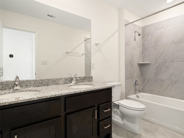 full bathroom featuring tile patterned floors, dual bowl vanity, tiled shower / bath, and toilet