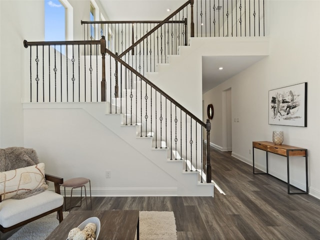 staircase with a high ceiling and wood-type flooring