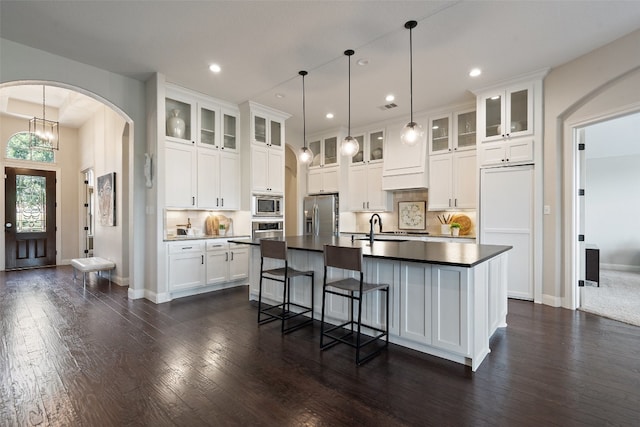 kitchen with backsplash, a kitchen island with sink, and dark hardwood / wood-style flooring