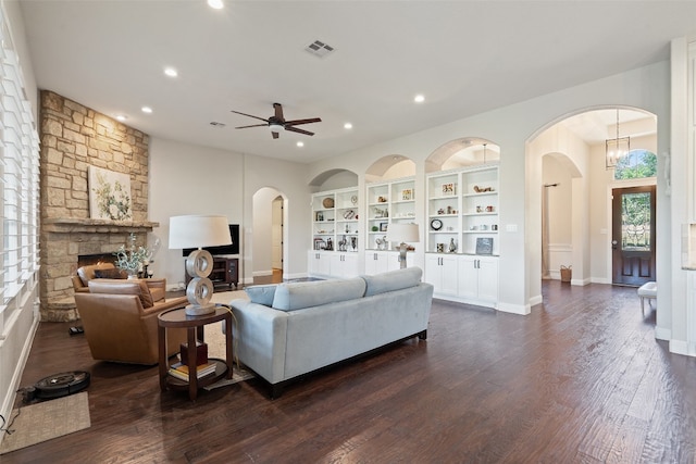 living room featuring ceiling fan, a stone fireplace, dark hardwood / wood-style flooring, and built in features