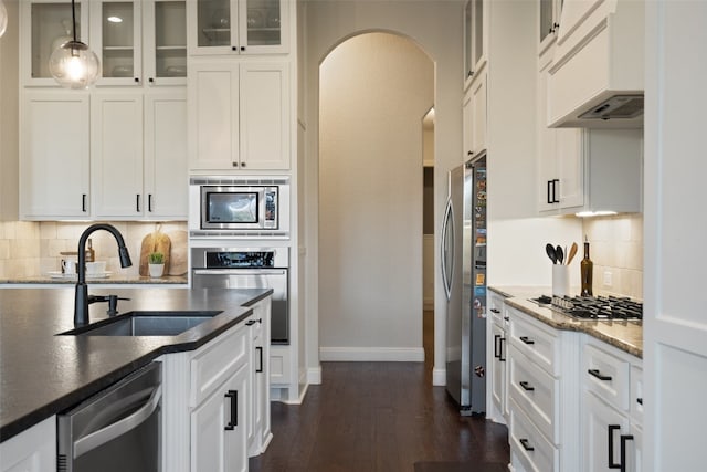 kitchen with backsplash, sink, appliances with stainless steel finishes, dark hardwood / wood-style floors, and pendant lighting