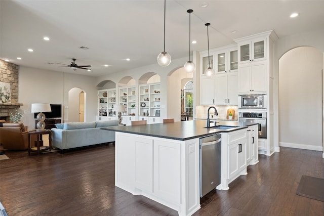 kitchen with dark hardwood / wood-style flooring, a center island with sink, white cabinetry, and stainless steel appliances