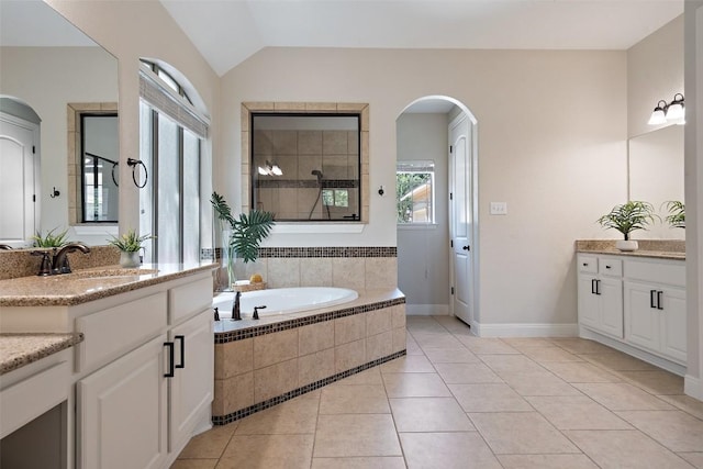 1104 Lions Lair, Leander, TX 78641 - bathroom with two vanities, a bath, tile patterned floors, vaulted ceiling, and a tile shower