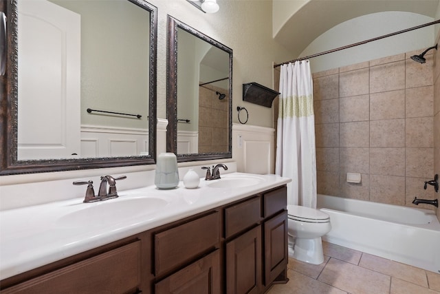 full bathroom with toilet, dual bowl vanity, shower / tub combo, and tile patterned floors