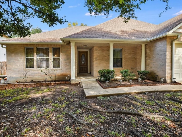 ranch-style house with a shingled roof, brick siding, and a porch