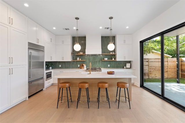 2109 Wordsworth Dr Unit 1, Austin, TX 78704 - kitchen with stainless steel built in refrigerator, open shelves, premium range hood, light wood-style floors, and light countertops