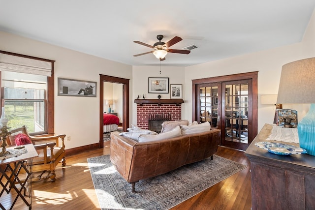 bedroom featuring hardwood / wood-style floors, french doors, ceiling fan, and a brick fireplace