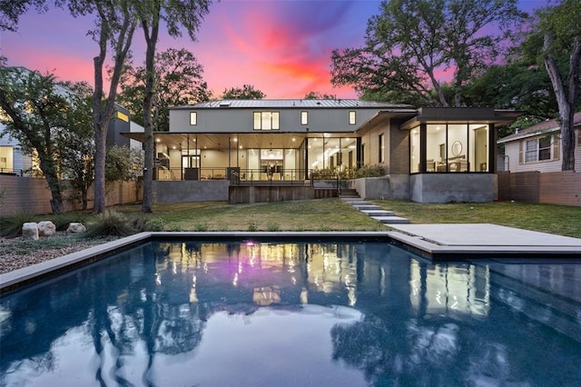 back of property with a fenced backyard, an outdoor pool, and a lawn