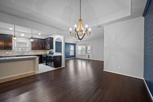 kitchen with stainless steel appliances, decorative light fixtures, tasteful backsplash, dark brown cabinets, and hardwood / wood-style flooring